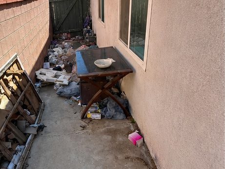 Narrow side path cluttered with a broken table, boards and bags
